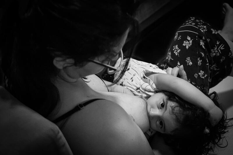 black and white image of woman nursing a toddler