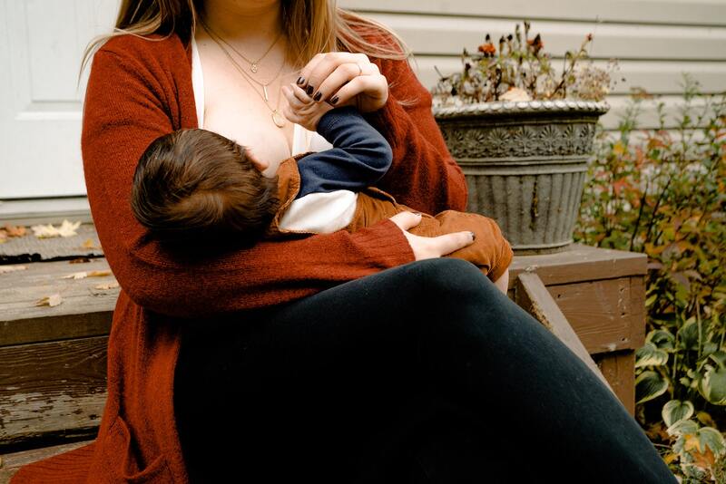 woman in orange sweater breastfeeding a baby
